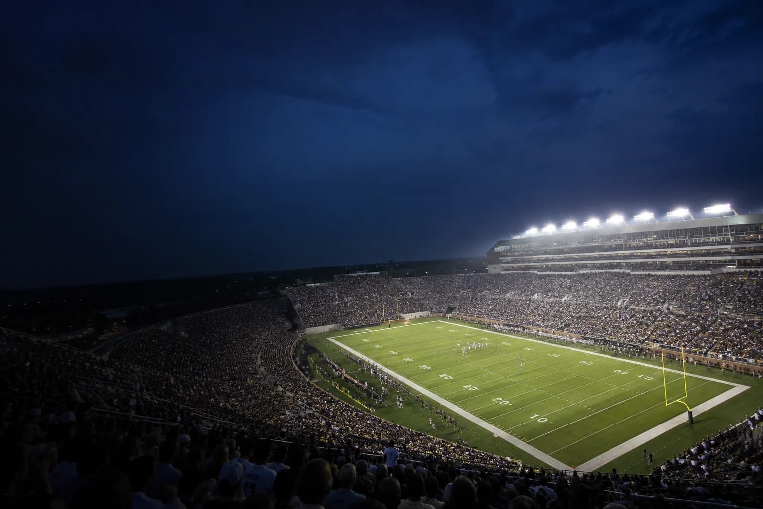 An illustrative American college football stadium under the lights